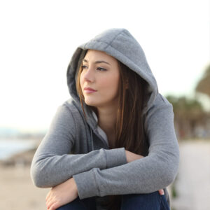 A teenage girl looking lonely on a beach.