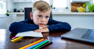 A child looking unhappy while home schooling.