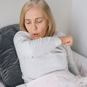 A woan in bed experiencing long COVID symptoms.