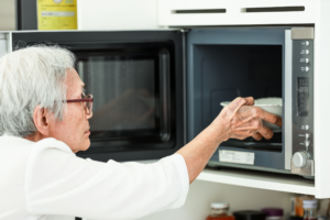 Photograph of an older person learning how to use a microwave.