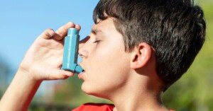 Young boy using asthma inhaler