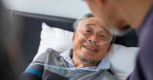 A general practitioner speaks with an elderly man in palliative care