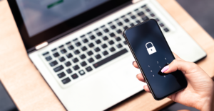 A person enters a password on their mobile phone to pass cyber security credentials on their laptop