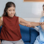 A nurse assists a middle-aged woman with arthritis lift up her arm