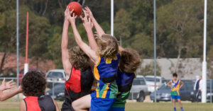 Junior Australian rules footballers jump to mark the ball